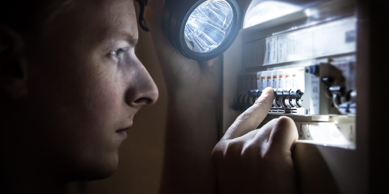 Man restoring power on circuit breaker after electricity outage emergency lighting