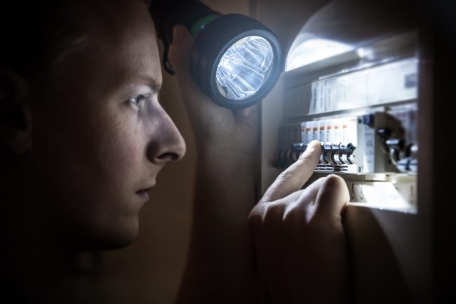 Man restoring power on circuit breaker after electricity outage emergency lighting